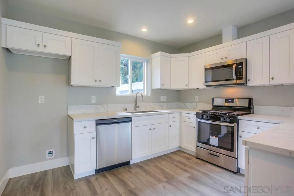 Kitchen with white cabinets, stainless steel appliances, dishwasher, and light wood floor