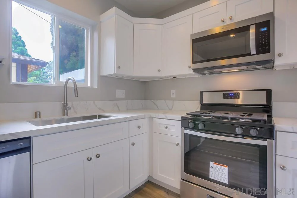 Kitchen with white cabinets, stainless steel stove, sink, and dishwasher.