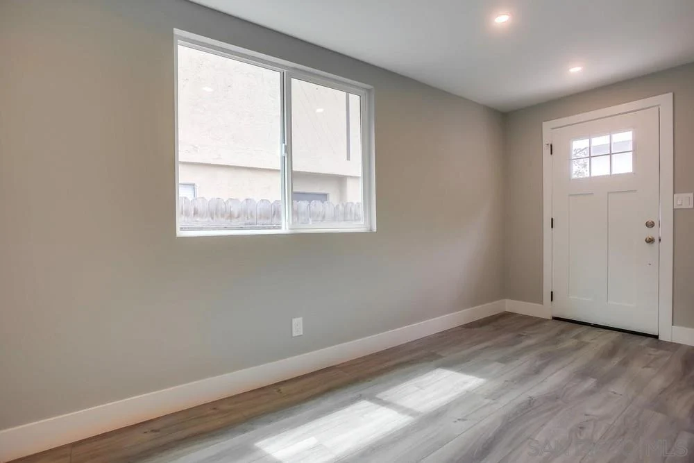 Room with light gray walls, hardwood floor, window, and door.