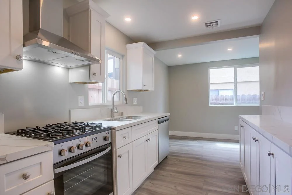 Kitchen with white cabinets, stainless steel stove, and window