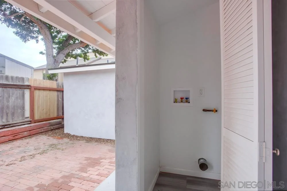 Indoor space with white walls, pipe on floor, and fenced yard outside.