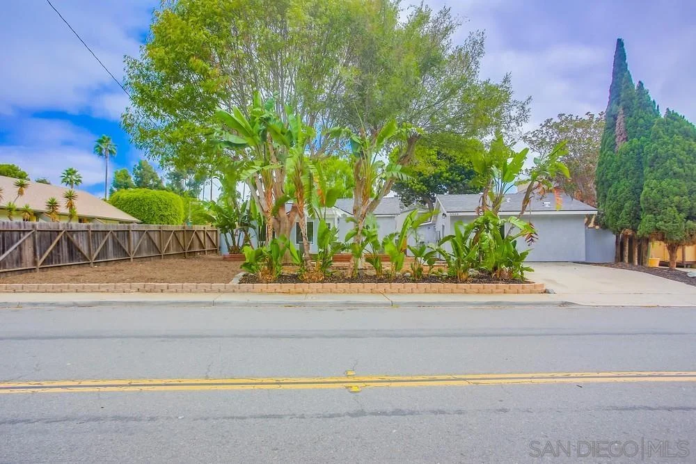 Front yard with landscaping, plants, and trees facing the street.