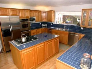 Kitchen with wood cabinets, tile counters, appliances, and island