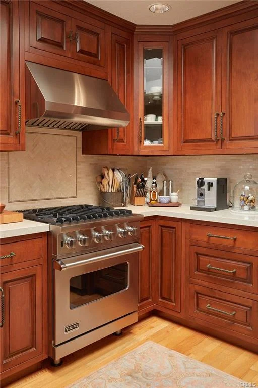 Kitchen with wooden cabinets, stainless steel stove, countertop with fruit, and window.