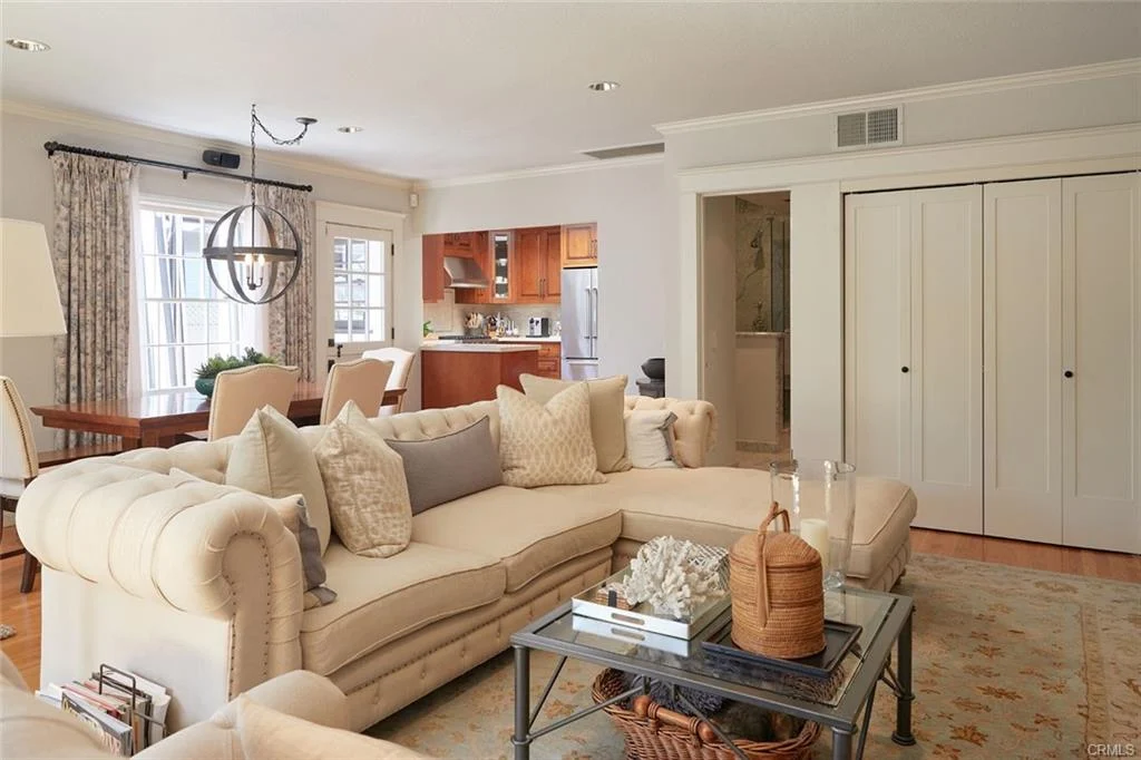Living room with sectional sofa, pillows, coffee table, dining area, and rug.