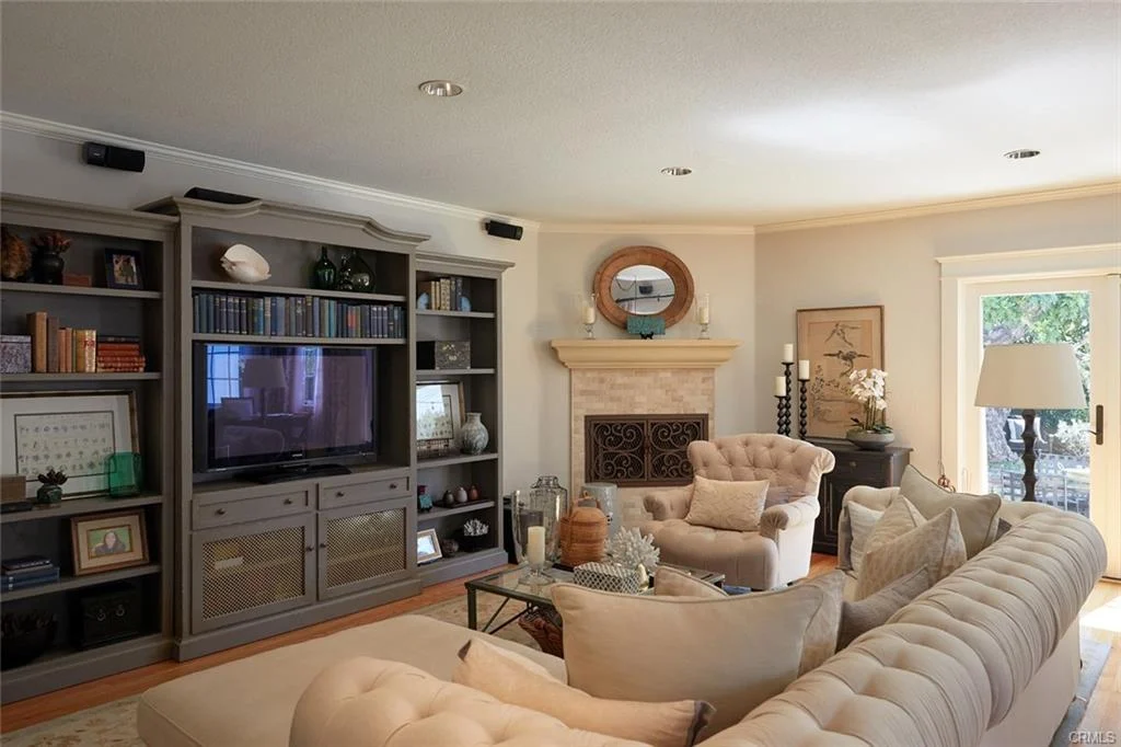 Living room with TV, bookshelf, sofas, coffee table, fireplace, and glass doors.