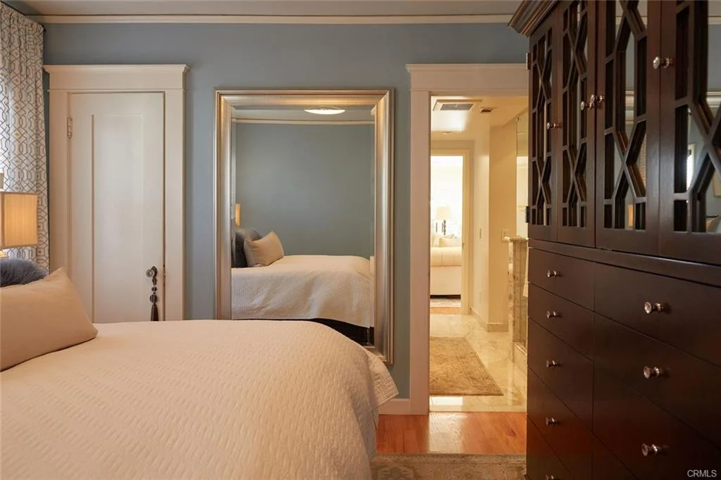 bedroom with bed, mirror, and dark wooden dresser.