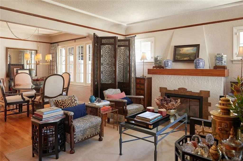 Living room with fireplace, seating, books, decor, divider, and windows
