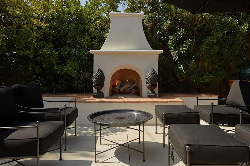 Outdoor seating with fireplace, chairs, table, and plants