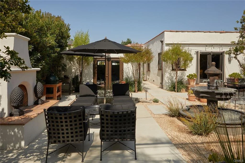 Patio with lounge chairs, umbrella, fountain, and plants