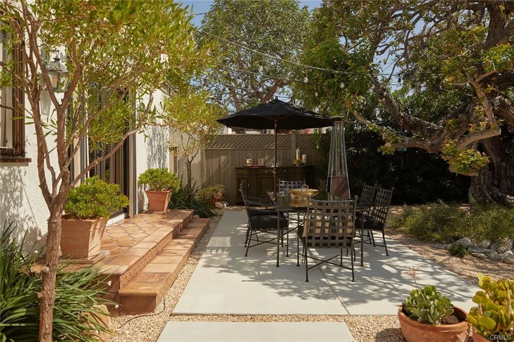 Patio with table, chairs, umbrella, plants, and trees