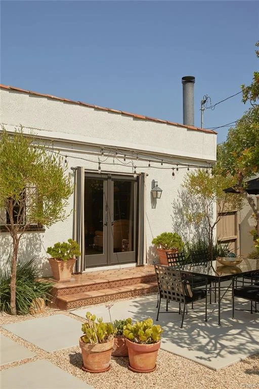 Courtyard with table, chairs, umbrella, plants, and sliding glass doors