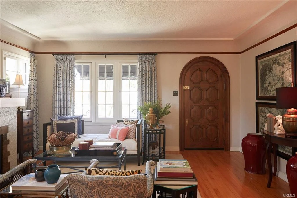 Living room with door, windows, plants, cushions, and furniture