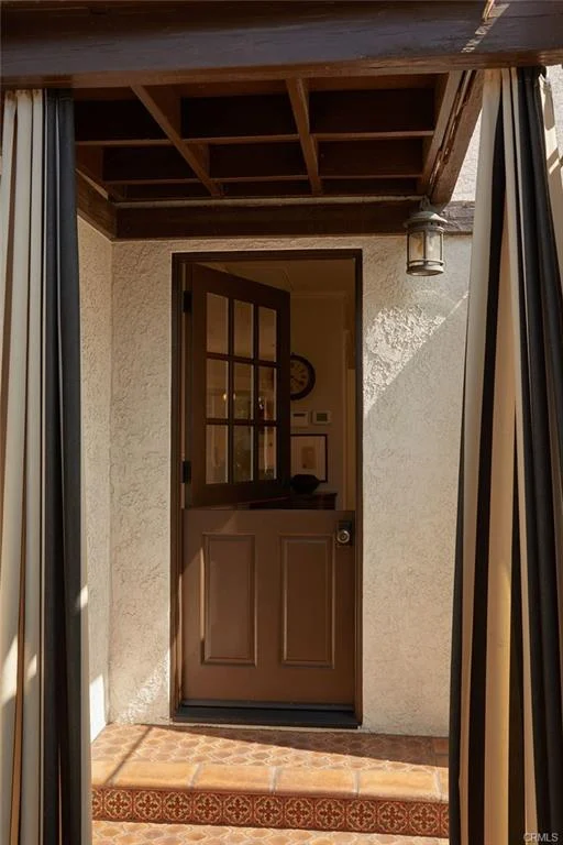 Open door with curtains and tile floor leading inside