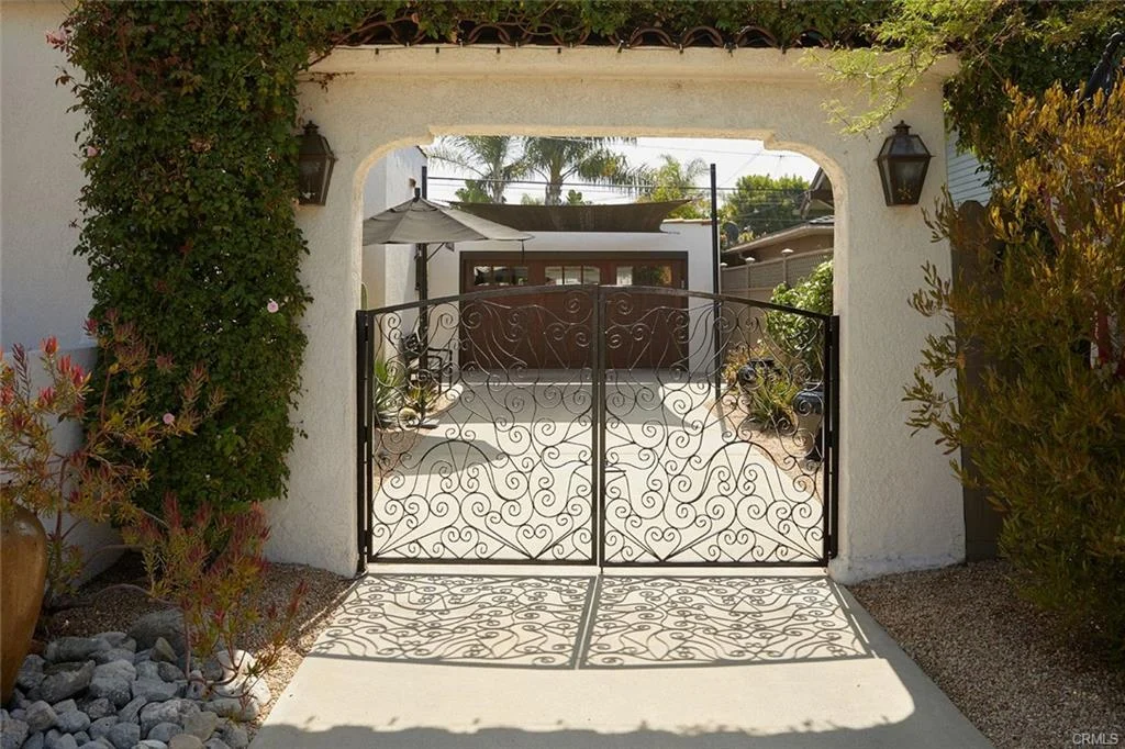 Wrought iron gate with paved courtyard, plants, and building in background