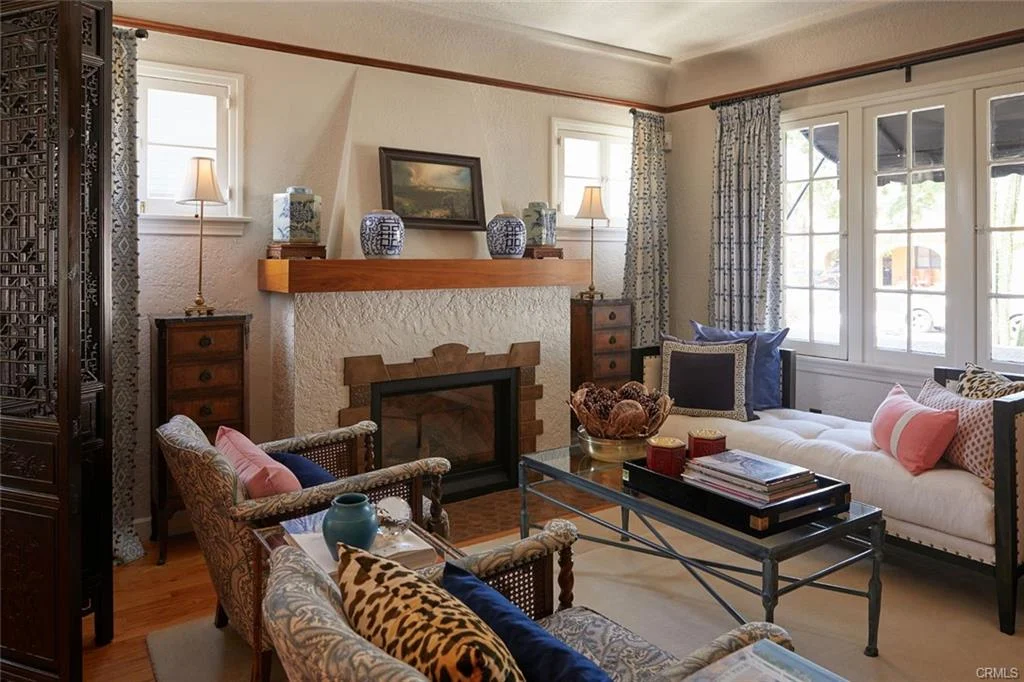 Living room with fireplace, chairs, daybed, coffee table, and windows