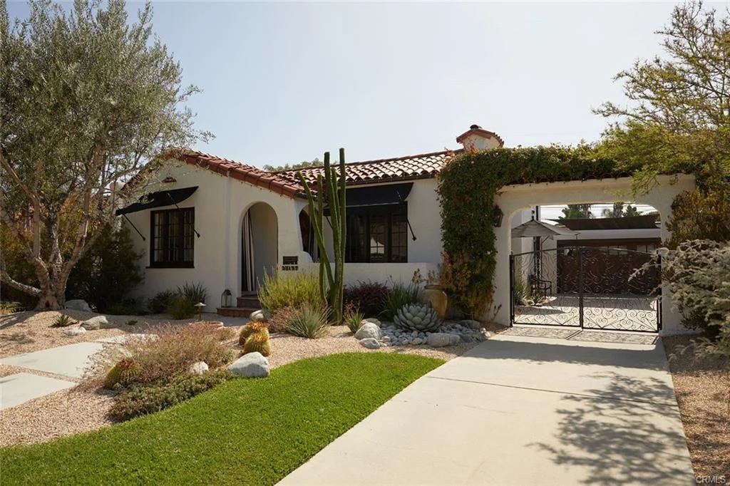 House in California real estate with tiled roof, plants, rocks, and gated entrance