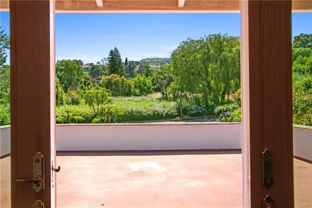 View from doorway with trees, plants, and hills.