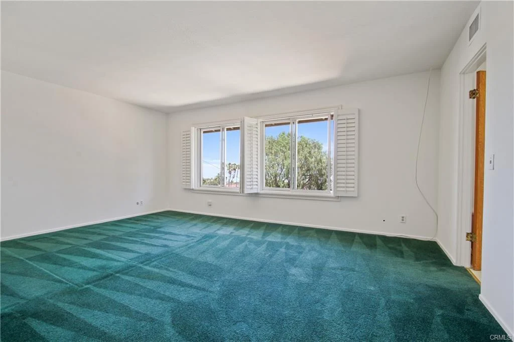 Room with green carpet, windows, and white wall.