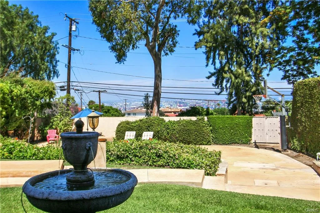 Garden with fountain, plants, and trees.