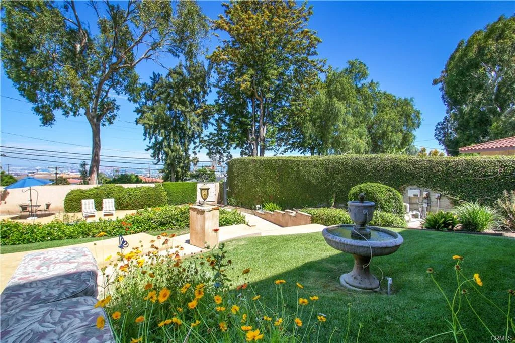 Garden with fountain, plants, and flowers.