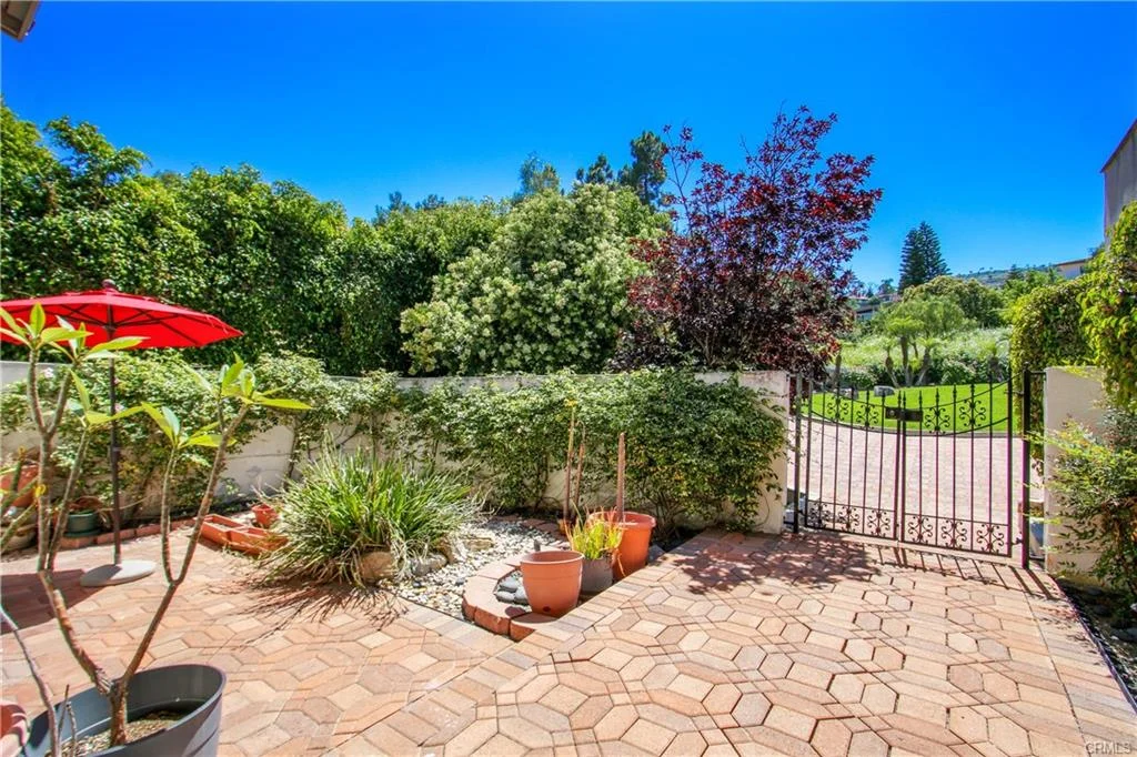 Outdoor patio with red umbrella, plants, and flower pots.