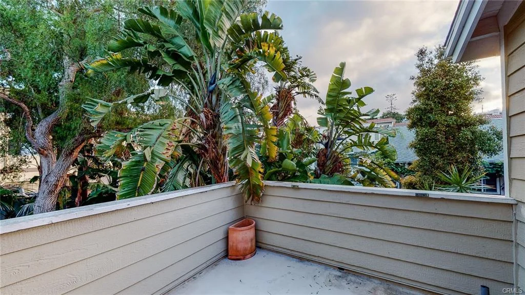 Balcony with beige railing and surrounding green plants and trees