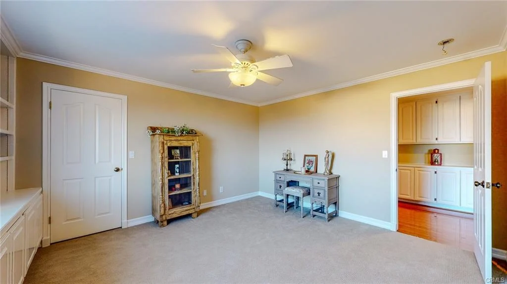 Room with carpet, ceiling fan, bookshelf, cabinet, desk with chairs, and window