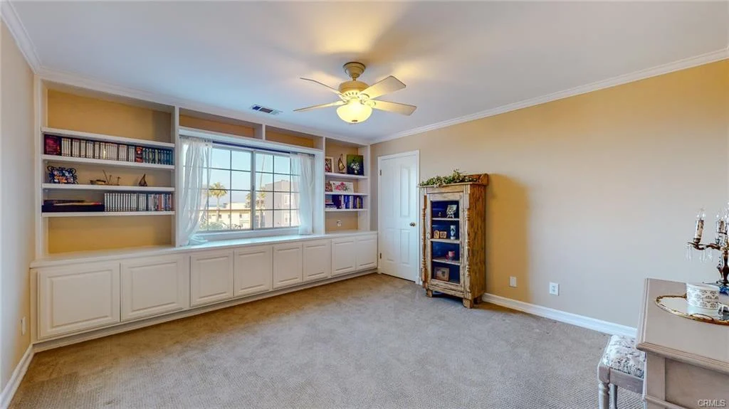 Bedroom with carpet, ceiling fan, built-in shelves, cabinet, and window