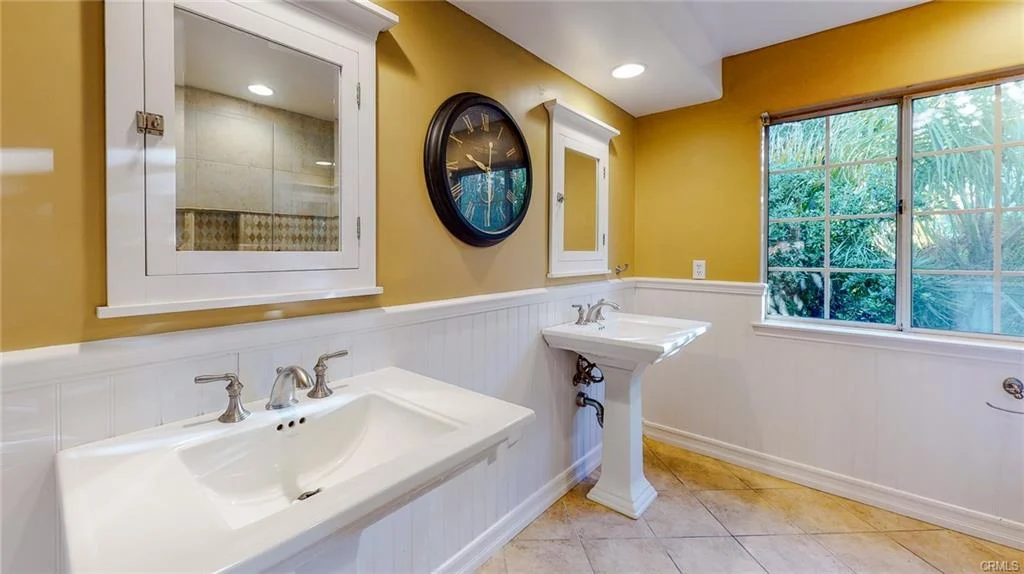 Bathroom with double sink, wall mirror, window, and tile floor