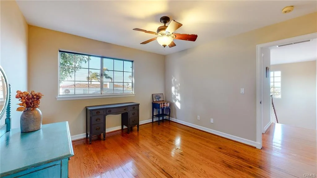 Room with hardwood floor, ceiling fan, window, desk, and entryway