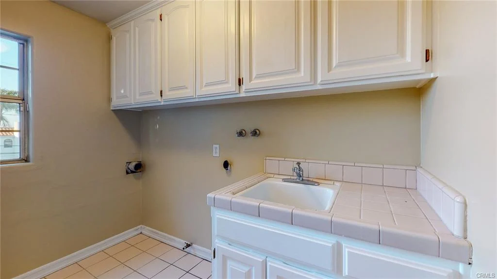 Laundry room with white cabinets and sink