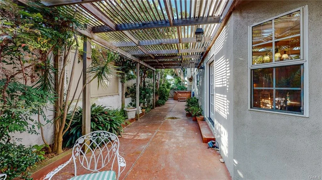 Pathway with plants, metal awning, chair, and nearby building