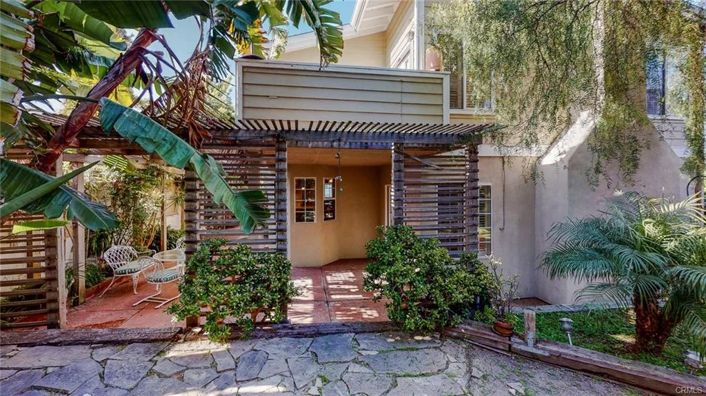 Courtyard entrance with wooden trellises, greenery, and stone pathway