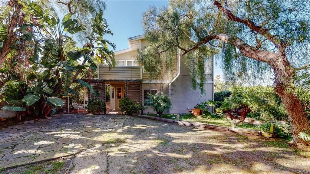 House with greenery, trees, and stone pathway to entrance California real estate
