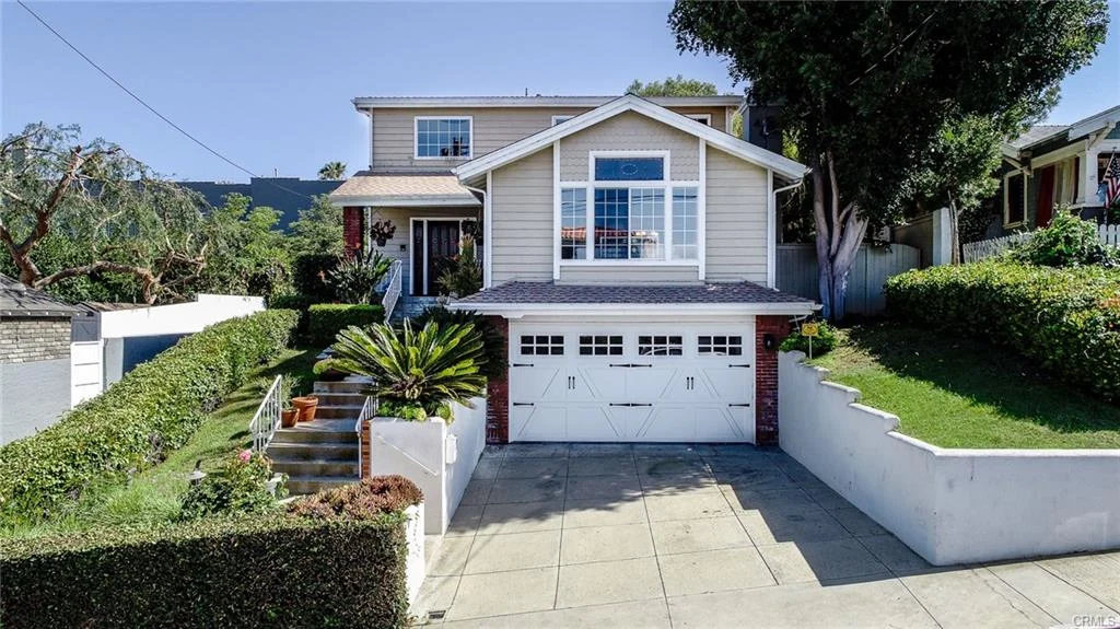 two-story house with peaked roof, front window, driveway, and landscaped yard California real estate
