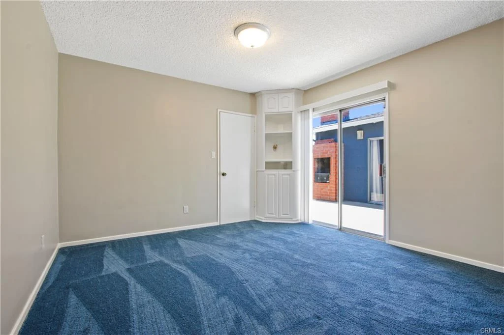 Empty room with blue carpet and a sliding glass door.