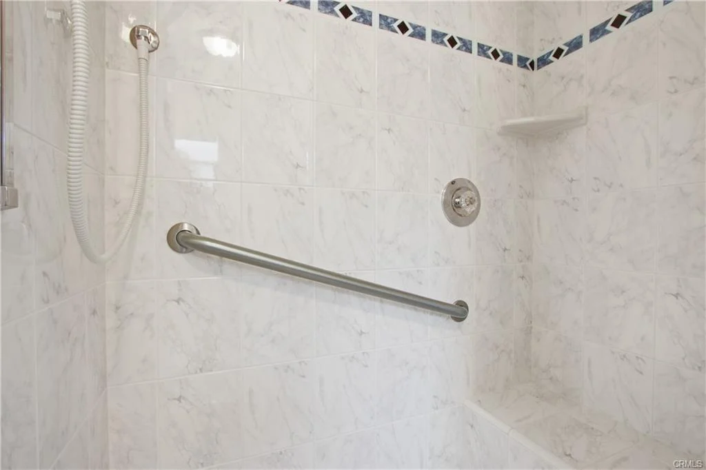 White shower with tiles and a showerhead.