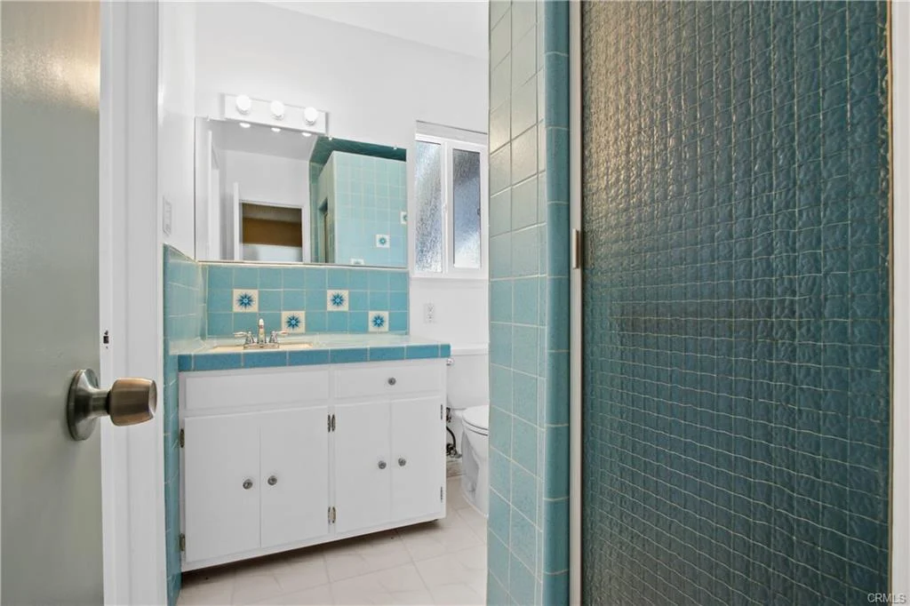 White bathroom with blue tiles and a glass shower.