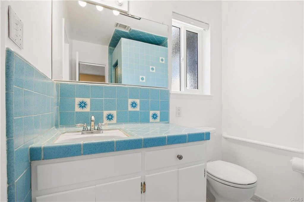 White bathroom with blue flower tiles and a sink.