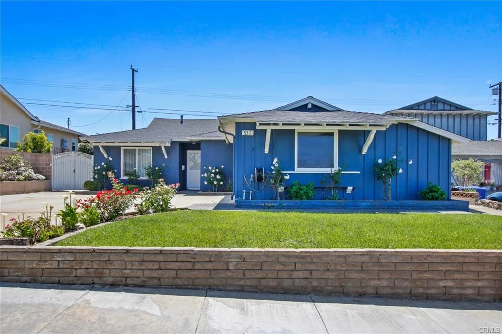 Blue California real estate house with a green yard.