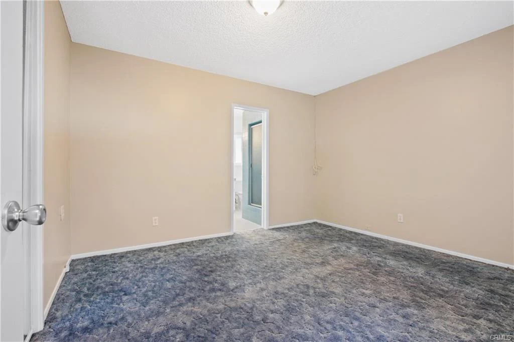Empty room with beige walls and blue carpet.