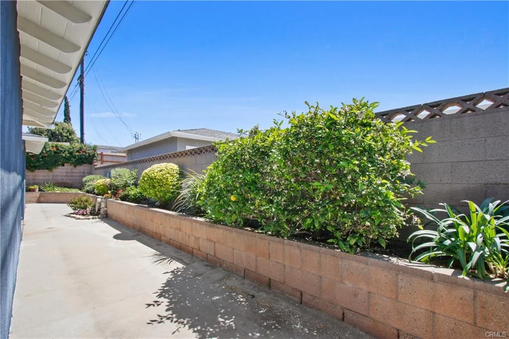 Outdoor area with concrete path, brick walls, and plants