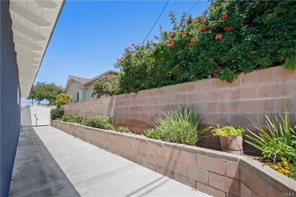Narrow path with plants and wall leading to a house California real estate