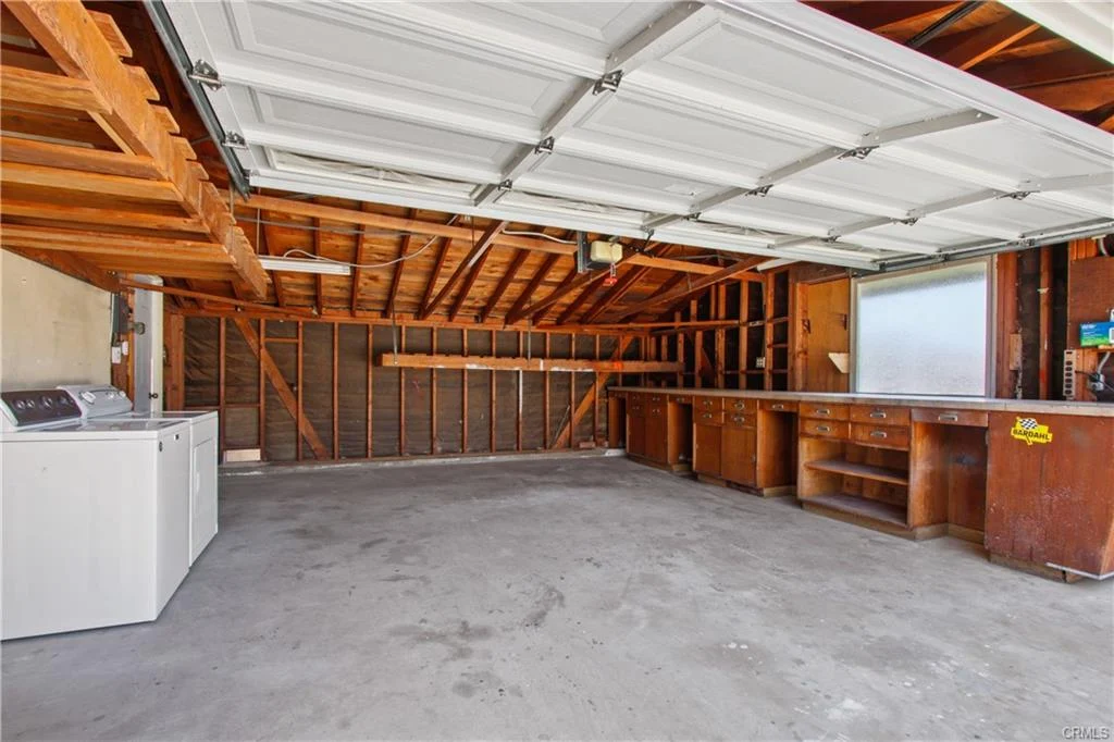 Garage with concrete floor, washing machine, and built-in cabinets