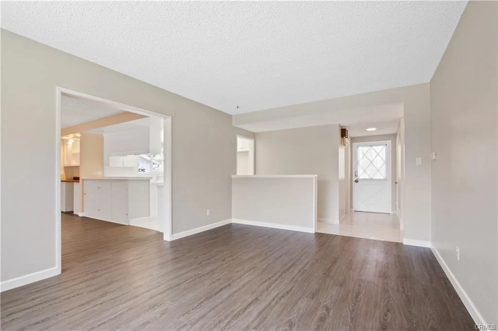 Empty room with wood floors and a door leading outside.