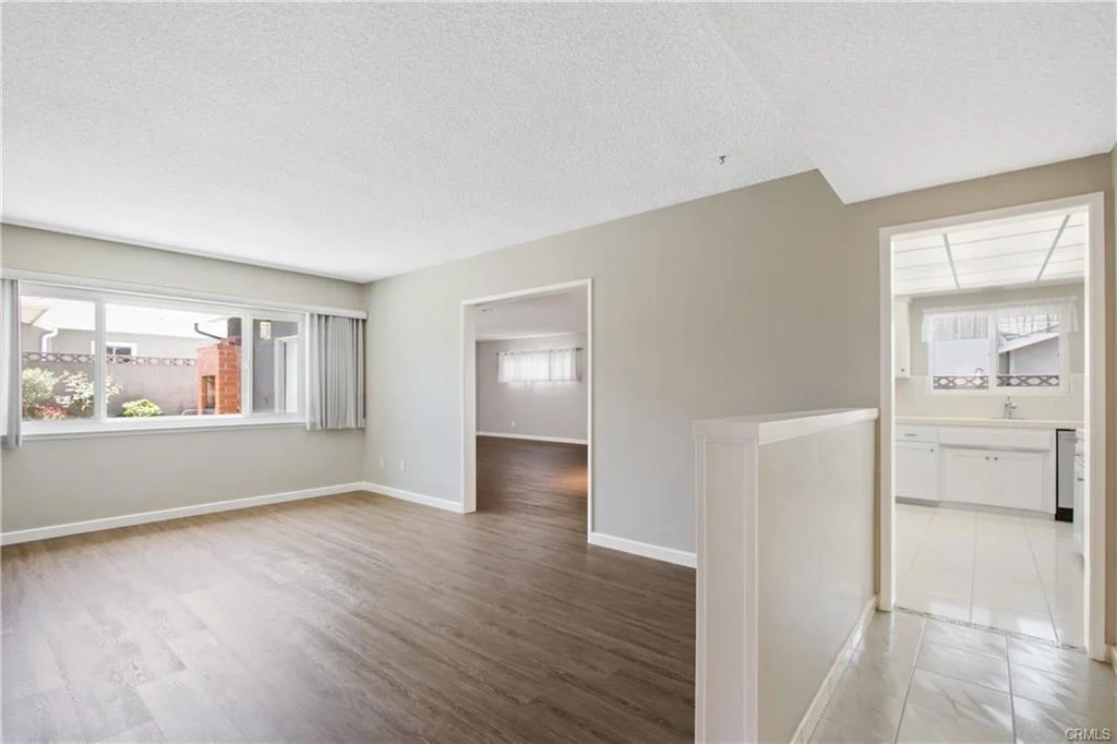 Empty room with wood floors and big windows.