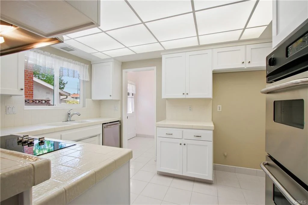 Bright white kitchen with tiles and a stove.