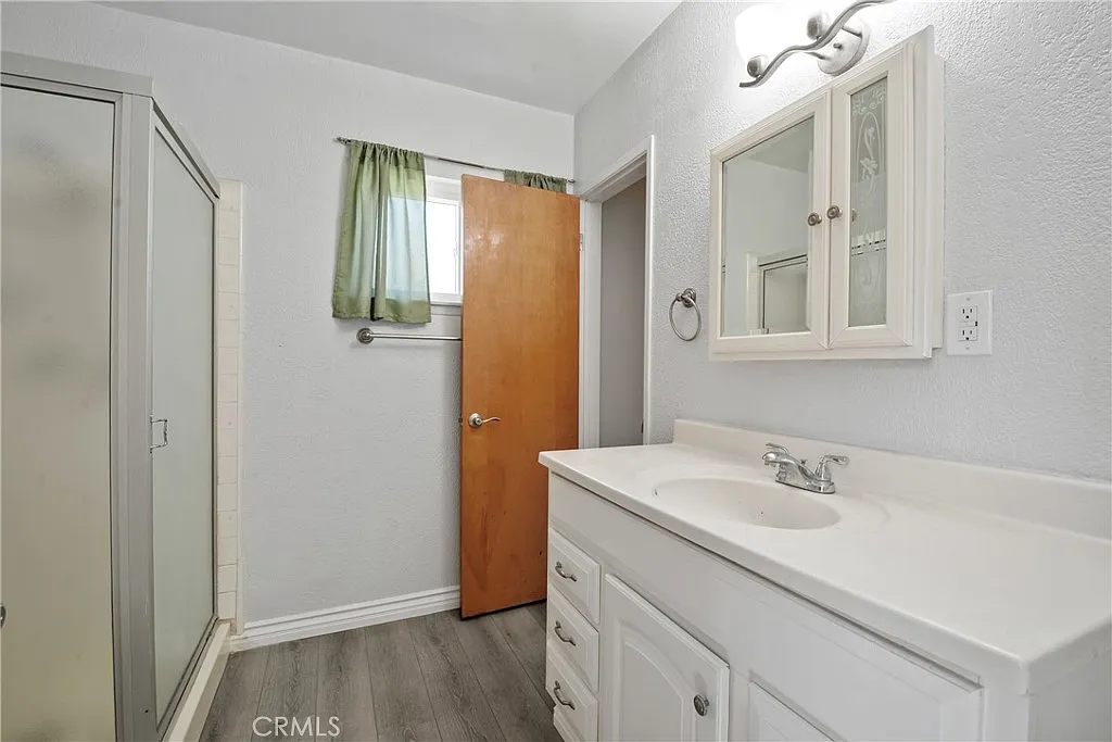bathroom with a shower, a sink, a mirror cabinet, and a door with a green curtain.