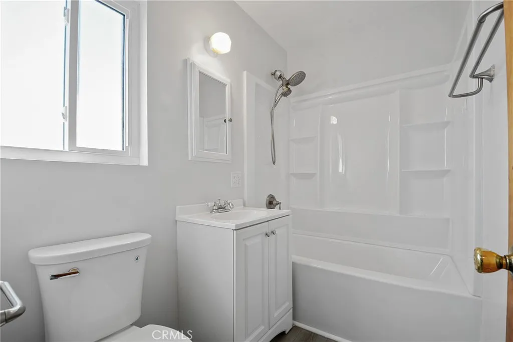 bathroom with a toilet, vanity, and a shower.